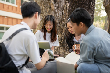 Group of happy young teen Asian students are talking and doing homework in a campus park together.