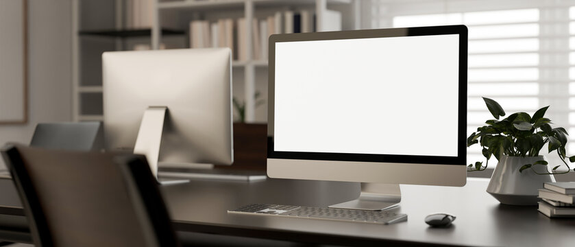 A white-screen PC computer mockup on a desk in a modern office room. workspace close-up image.