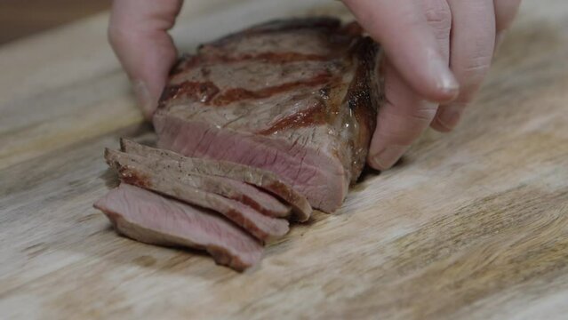 Chef cutting beef steak into slices, for argentine barbecue with chimichurri and cafe de paris butter sauce