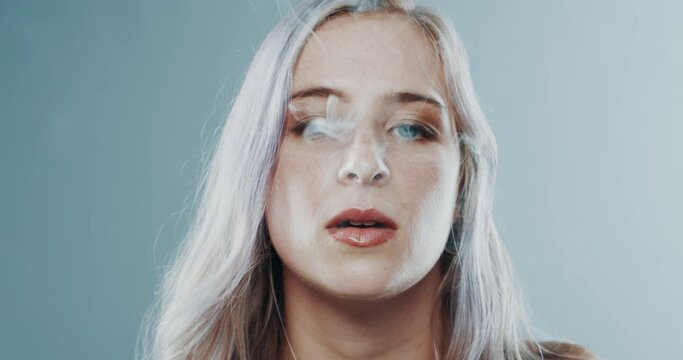 Weed, marijuana and woman with smoke in mouth with legal drugs, addiction and relax with a joint. Smoking, blunt and portrait of person high with cannabis, pot and substance abuse in blue background
