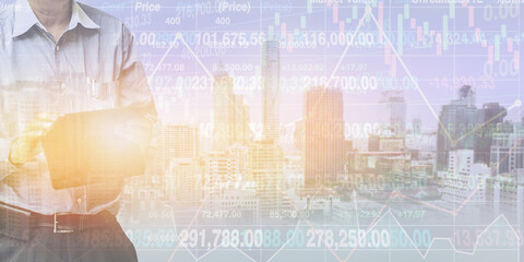 Businessman  standing and operate tablet to control stock financial index data on blurry urban real estate background with graph and chart.Double exposure  background for business presentation. - 694652503