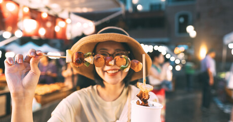 Focus on barbeque asian foodie woman eating bbq grilled skewers at outdoor night market street food