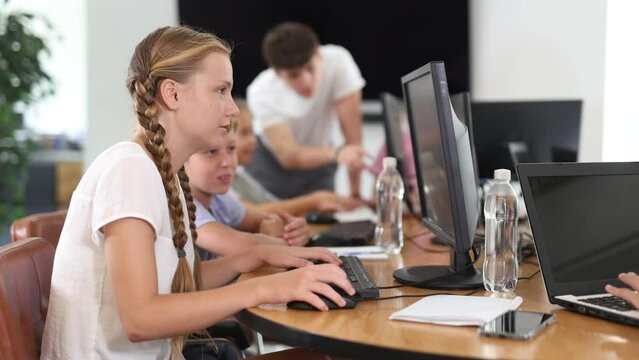 Curious underage girl and boy engaged in IT training during computer courses for children
