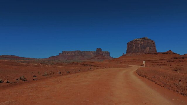 Driving through Monument Valley in Utah and Arizona. Red rock formations in iconic scenic wild west landscape.
