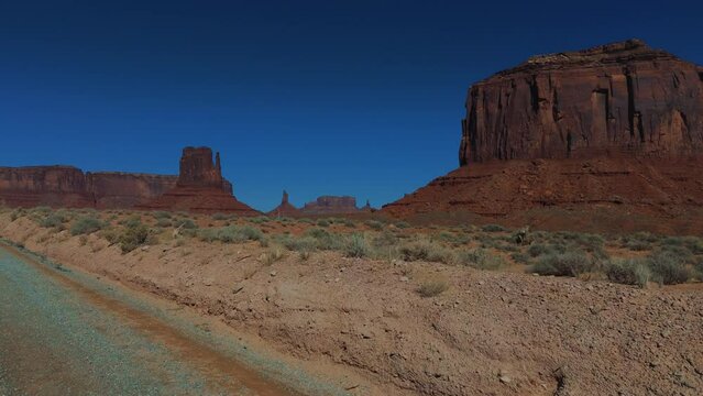 Driving in Monument Valley in Utah and Arizona. Red rock formations in iconic scenic wild west landscape.