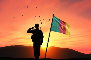 Silhouette of a soldier with the Cameroon flag stands against the background of a sunset or sunrise. Concept of national holidays. Commemoration Day.