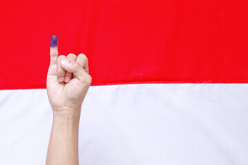 Man's little finger after voting on Indonesia's presidential election against Indonesia flag