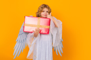 Angel kid with gift box present. Cute angel child, studio portrait. Angel kid with angels wings,...