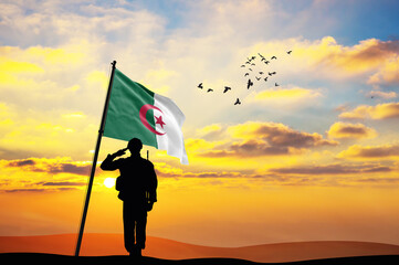 Silhouette of a soldier with the Algeria flag stands against the background of a sunset or sunrise. Concept of national holidays. Commemoration Day.