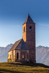 Hafling, Italy - The mountain church of St. Catherine (Chiesa di Santa Caterina) near Hafling - Avelengo on a warm autumn sunset with the Italian Dolomites in South Tyrol at background