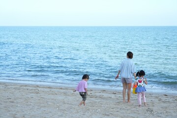 Naklejka premium Afternoon beach front with a family tourist ,mother hand holding her childs walking along the beach,one child hand holding bucket for sand playing ,beautiful beach front at ChaAm beach.