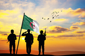 Silhouettes of soldiers with the Algeria flag stand against the background of a sunset or sunrise. Concept of national holidays. Commemoration Day.