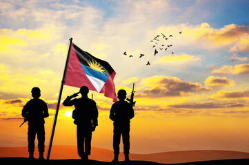 Silhouettes of soldiers with the Antigua and Barbuda flag stand against the background of a sunset or sunrise. Concept of national holidays. Commemoration Day.