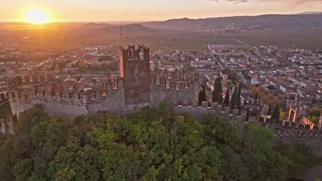 Scaliger Castle Overlooks The Historic Town Between The Medieval Walls In Soave, Italy During Sunset. - aerial cinematic shot