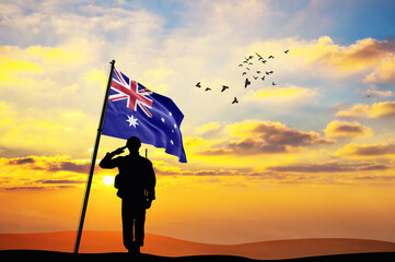 Silhouette of a soldier with the Australia flag stands against the background of a sunset or...