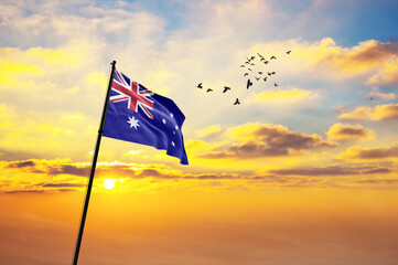 Waving flag of Australia against the background of a sunset or sunrise. Australia flag for Independence Day. The symbol of the state on wavy fabric.