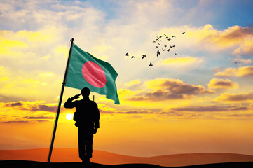 Silhouette of a soldier with the Bangladesh flag stands against the background of a sunset or...