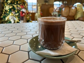 A cup of hot chocolate with a slice of lemon on a hexagonal table in a restaurant