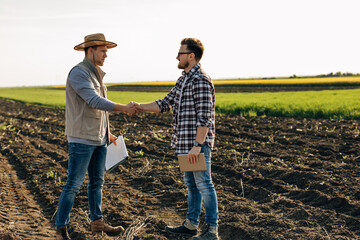 Agronomists shaking hands in the field.