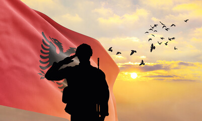 Silhouettes of soldiers with the Albania flag stand against the background of a sunset or sunrise. Concept of national holidays. Commemoration Day.