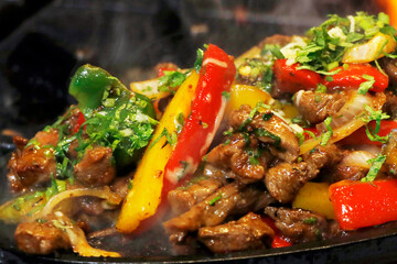 mexican food smoking chicken and beef fajitas on hot sizzling plate