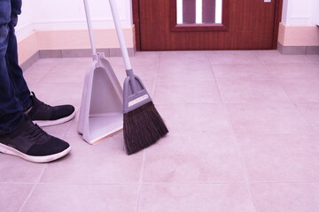 玄関内にてほうきで掃除する写真。ゴミ取り、掃除、清潔感、家事、管理をイメージ