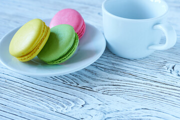 Colorful macaroons on a white plate and cup of coffee