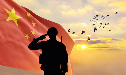 Silhouette of a soldier with the China flag stands against the background of a sunset or sunrise....