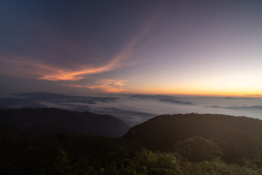 Early morning night sky from the top of Doi Luang Chiang Dao in Chiang Mai, Thailand overlooking a glowing town lights and beautiful dark blue sky