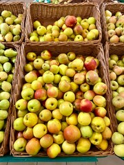 Apples in a basket are on the shelf of a store, selling fruits in a supermarket, laying out goods on a shelf.