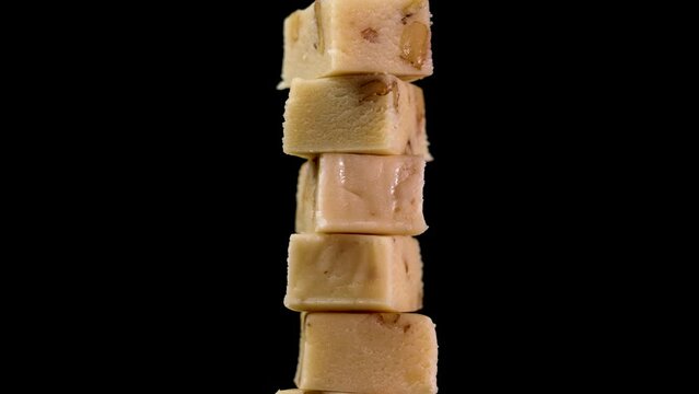 Typical sliced Spanish turron with nuts. Stacked traditional Christmas treats on a black background. Rotation