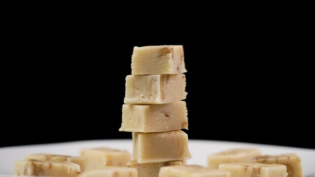 Sliced typical spanish nougat turron with almonds stacked on a black background. Rotation