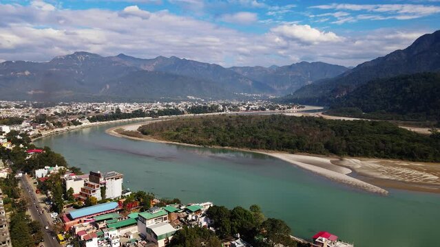 A bird's-eye view of Rishikesh City in Uttarakhand surrounded by lush green hills on a cloudy day. It is a hilly Indian town located along the Ganges River. Beautiful Indian city.