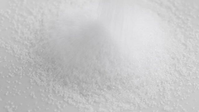 Stevia sugar powder pouring on a white sweetener pile in slow motion close up