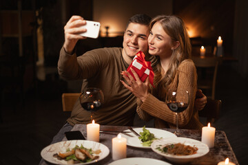 Happy couple taking selfie having romantic dinner in restaurant posing for photo