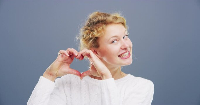 Happy woman, heart hands and love in care, support or compassion isolated against a studio background. Portrait of female person or blonde smile showing emoji or icon for romantic gesture on mockup