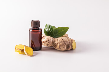 Ginger root essential oil in a medical bottle with a cap on a white background with slices and...