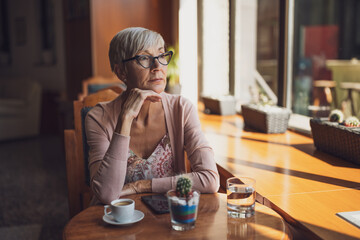 Mature woman is sitting in cafe and relaxing.