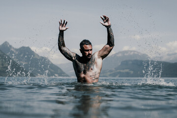 Sexy naked muscular Hispanic man splashing water in lake. Attractive male sexy model in water. Handsome boy rest in Alps lake water. Sexy man naked torso in water. Man freedom lifestyle. Strong - obrazy, fototapety, plakaty