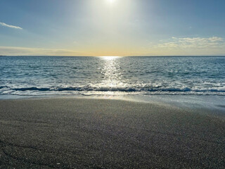 Obraz premium 大きな海に波が打ち寄せ、青い大空と太陽と夕日が混ざり合い、高台から見下ろす実写写真