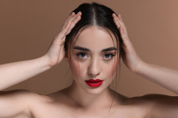 Naklejka premium Portrait of beautiful young woman with red lips on brown background, closeup