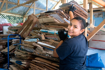 Young Hispanic Woman Stacking Cardboards, Eye Contact with Camera
