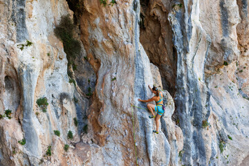 A young and strong woman is rock climbing on a rock.