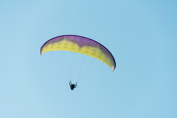 Beautiful picture of a paraglider gliding on a clear blue sky.