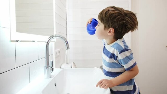 Nasal irrigation. Kid making nasal wash with saline. A young child boy uses the Neti Pot to treat runny nose. Nasal lavage. An Irrigation can. Sinus problem. Nasal allergies. Home bathroom background