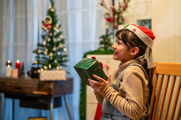 Obraz na płótnie Canvas Asian young daughter opening present gift box during Christmas season.
