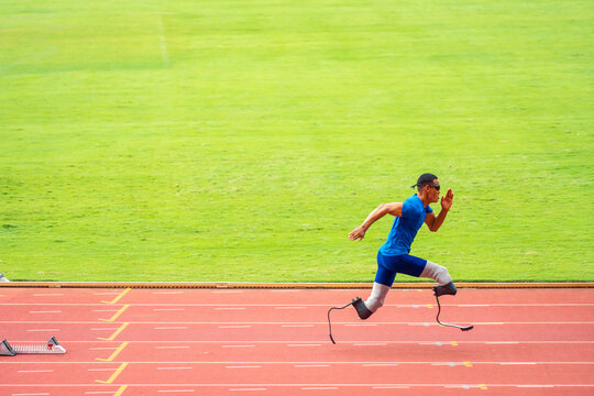 Asian para-athletes disabled with prosthetic blades running at stadium. 