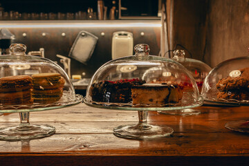 Glass pot with macarons and cakes. Cake shop interior. Cheesecake and macaroons in showcase. Pastry shop with dessert in glass. Bakery cafe. Sweet food. Desserts for the breakfast.