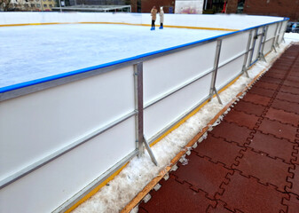 Ice hockey is a team sport played on ice skates, usually on an ice skating rink with lines and markings specific to the sport. portable yellow line around plastic guardrails