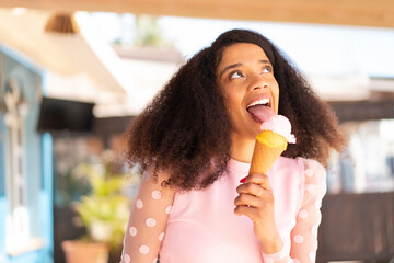 Young African American woman with a cornet ice cream at outdoors